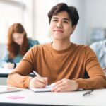 Smiling asian student sitting at desk in classroom