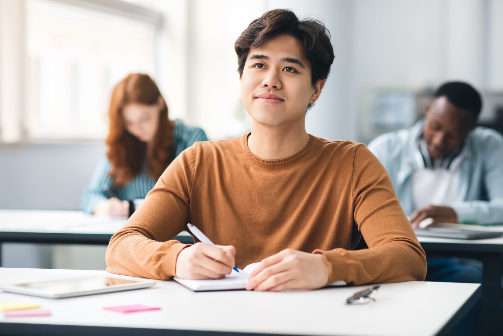 Smiling asian student sitting at desk in classroom